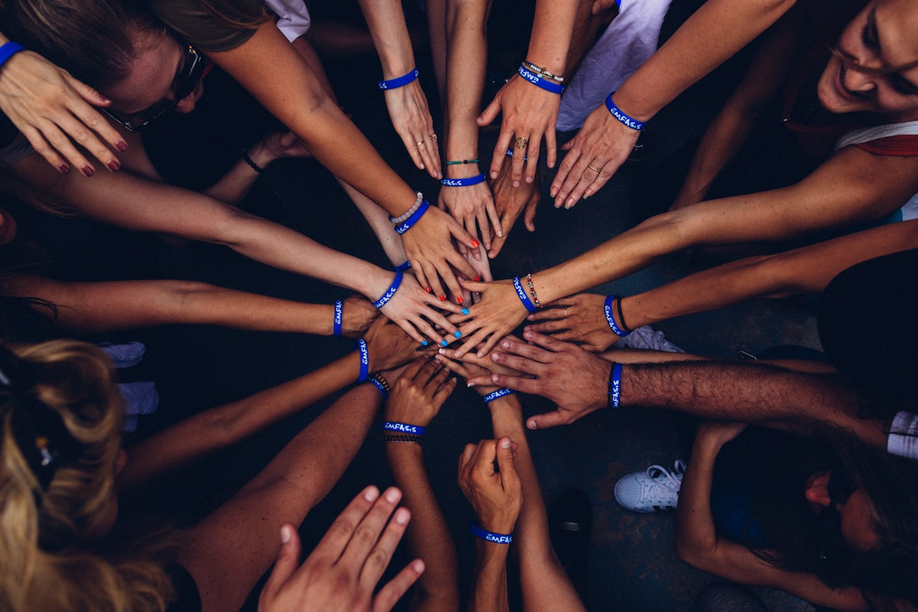 Many diverse hands joined together in a circle, symbolising unity and community
